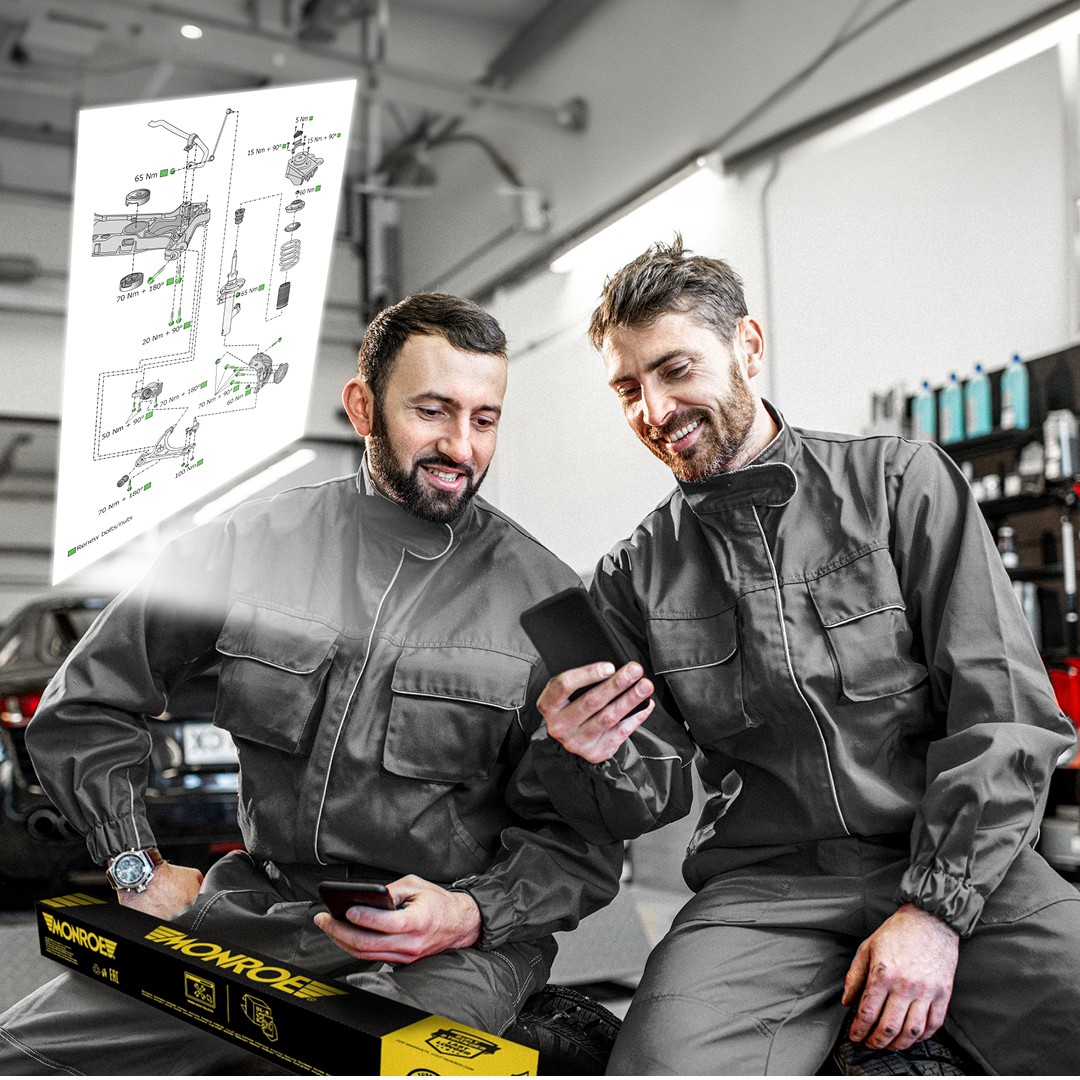 QRCode_Technical_Drawing Monroe2 Two automotive mechanics in a workshop examining detailed Monroe technical drawings accessed by scanning a Monroe QR code on the product packaging.