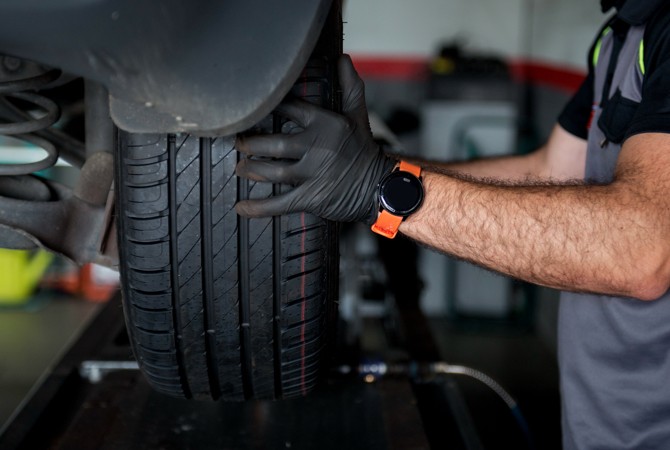 Auto Technician Inspecting Tire on Vehicle Auto Technician Inspecting Tire on Vehicle