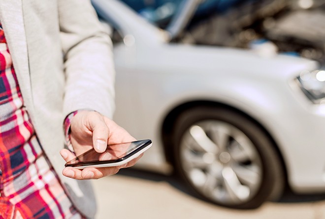 person-holding-phone-car-in-background