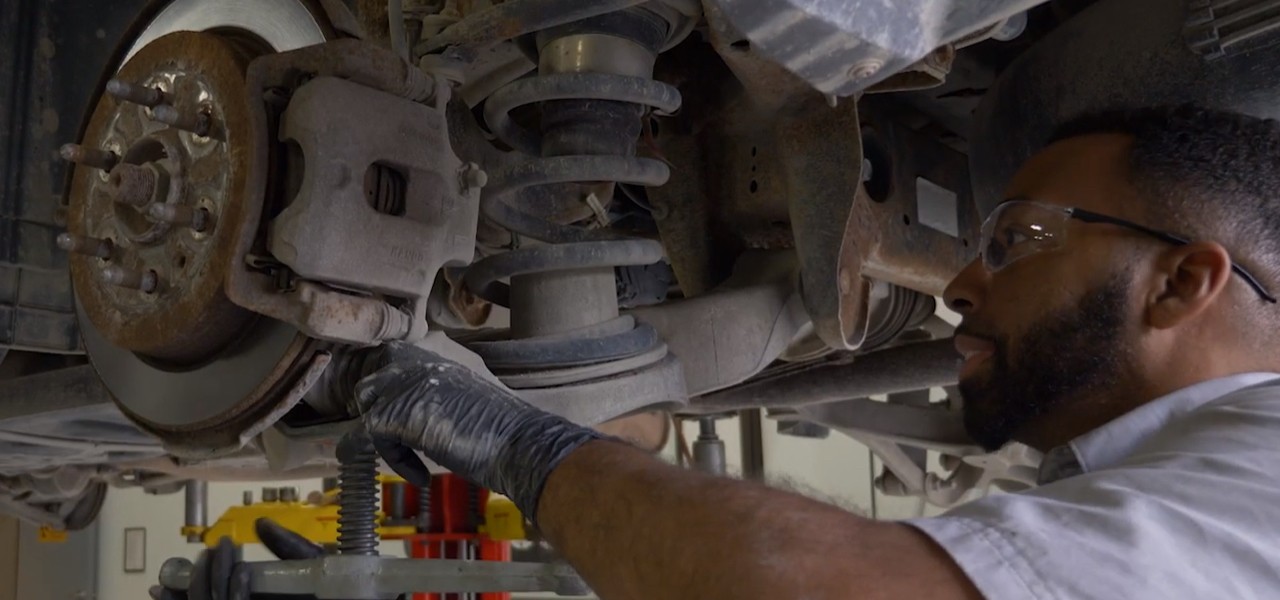 Auto technician installing shock on vehicle Auto technician installing shock on vehicle