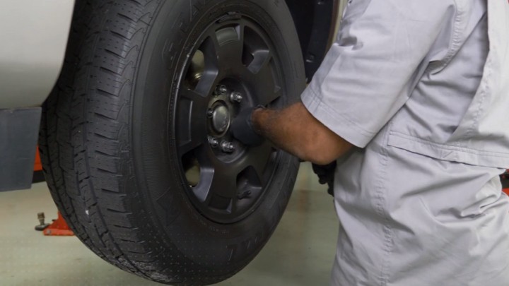 install-struts-chevy-silverado-gmc-sierra-1500-step-1 Technician removing the front wheel from a vehicle on a lift
