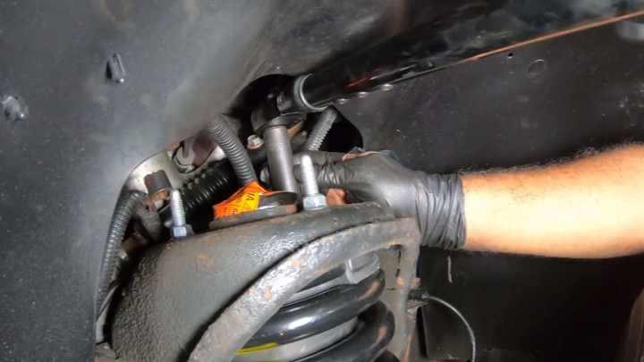 install-struts-chevy-silverado-gmc-sierra-1500-step-12 Technician loading the suspension and tightening upper mounting nuts